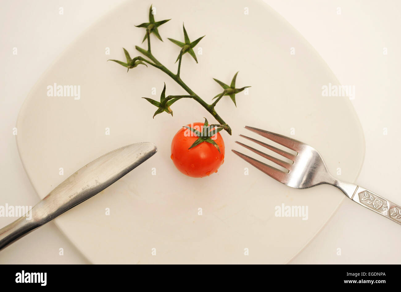 Tomato on Plate with Cutlery Stock Photo