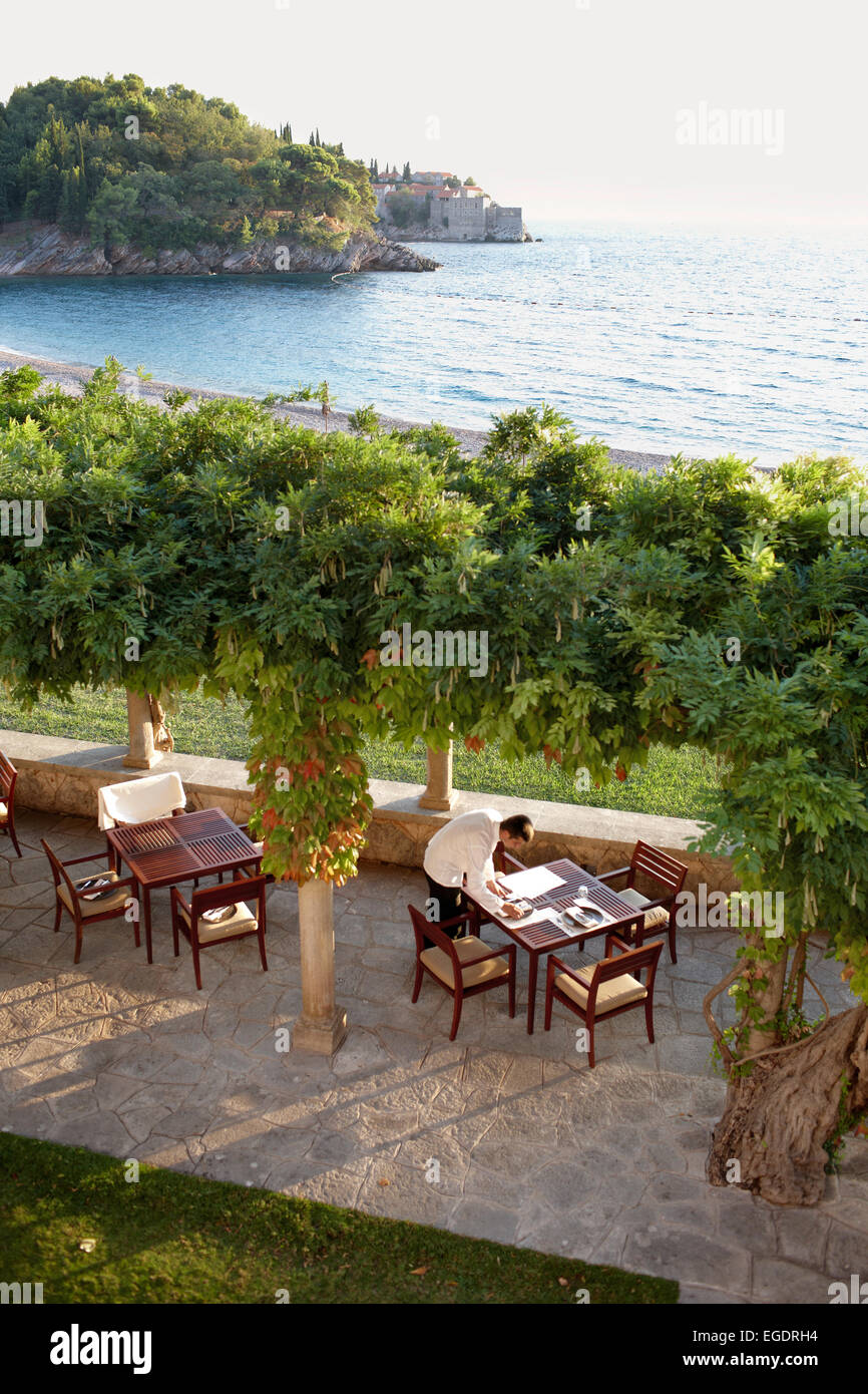 Waiter setting a table on terrace of Villa Milocer, Aman Sveti Stefan, Sveti Stefan, Budva, Montenegro Stock Photo