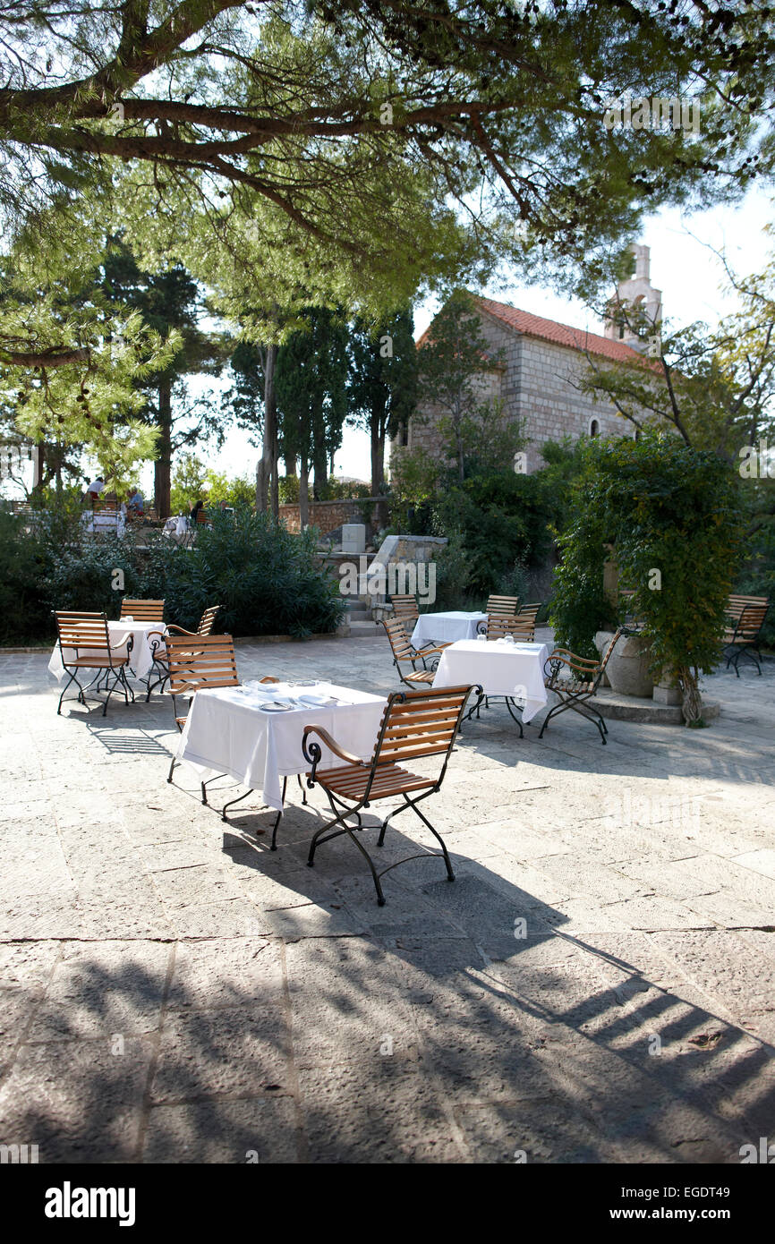 Coffee tables on the Piazza under trees, Aman Sveti Stefan, Sveti Stefan, Montenegro Stock Photo