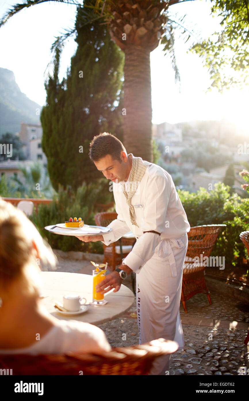 Waiter serving a drink on a terrace of a bistro, Deia, Majorca, Spain Stock Photo