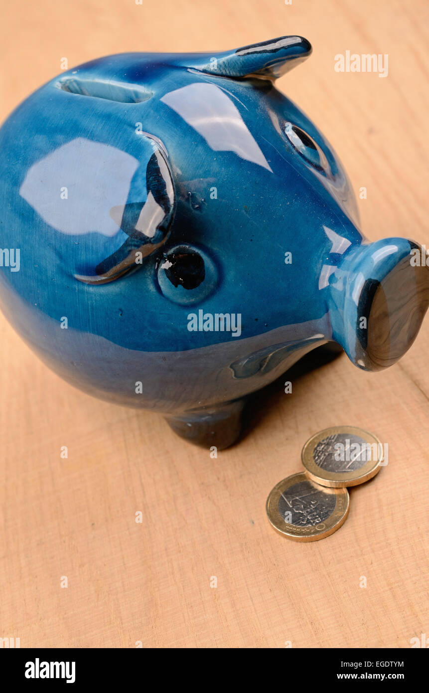 Blue old piggy bank with coins on a wooden table Stock Photo - Alamy