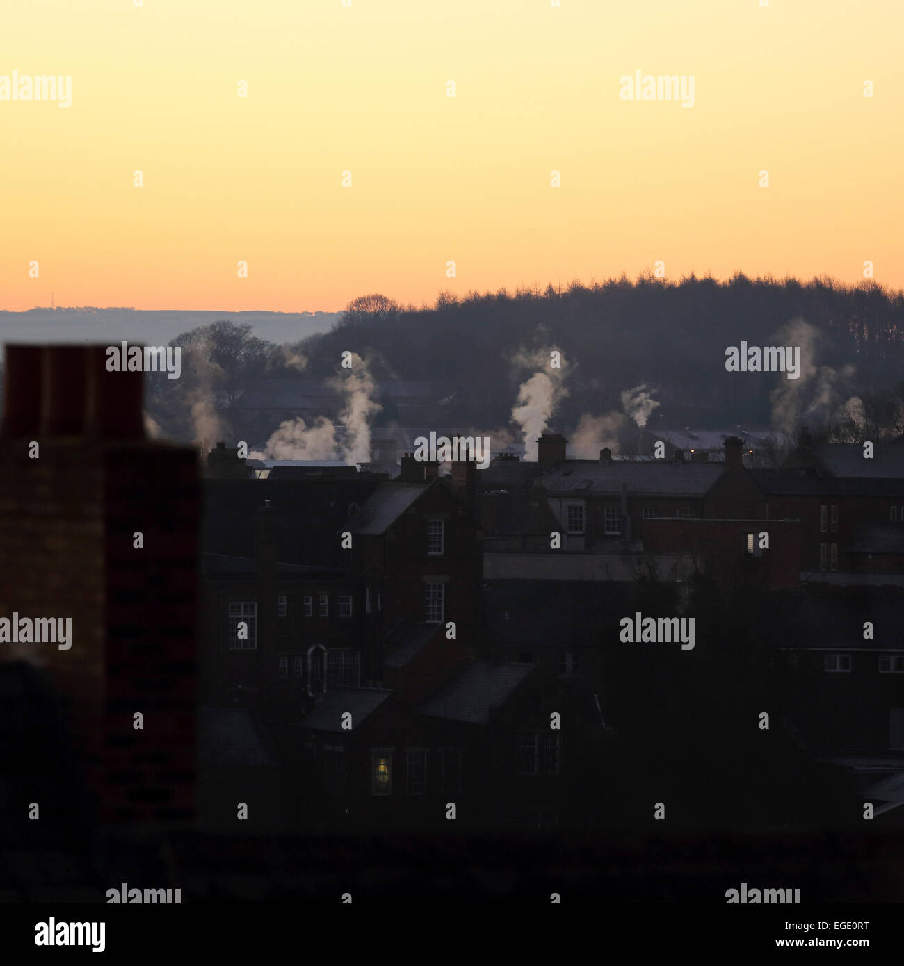 Daybreak over houses in Durham City, England. Smoke rises from chimneys in the morning light. Stock Photo