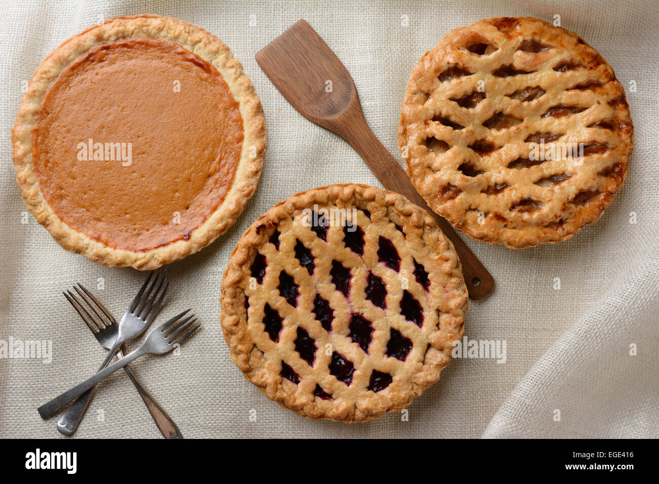 High angle shot of three fresh baked homemade pies, Apple, Cherry and Pumpkin on a burlap table cloth. Horizontal format with fo Stock Photo
