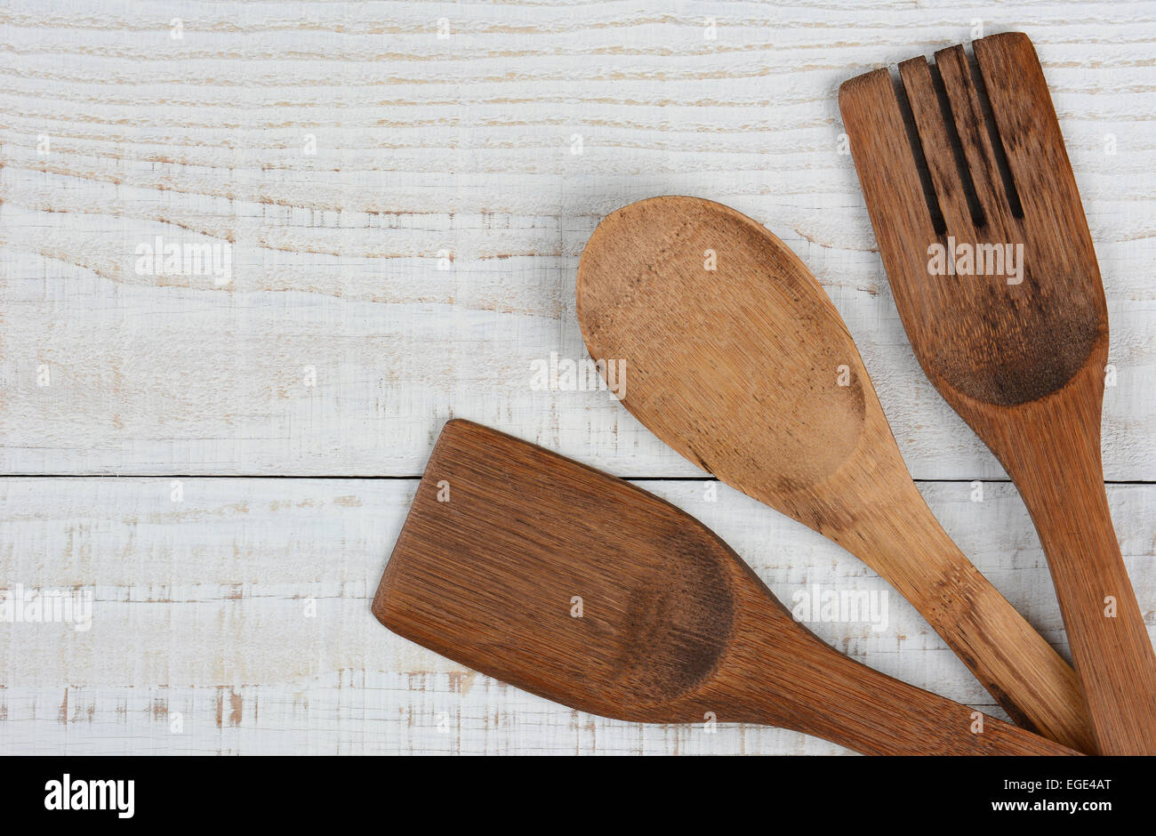 High angle shot of three wooden kitchen utensils in the lower right corner of the frame. The spoon, fork, and spatula have their Stock Photo