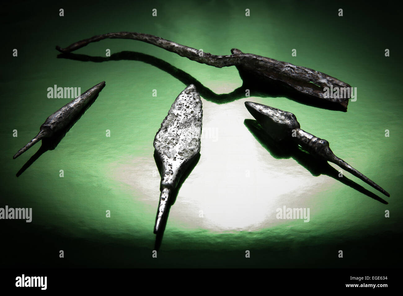Ancient scissors and arrows on a brilliant green background in a beam ...