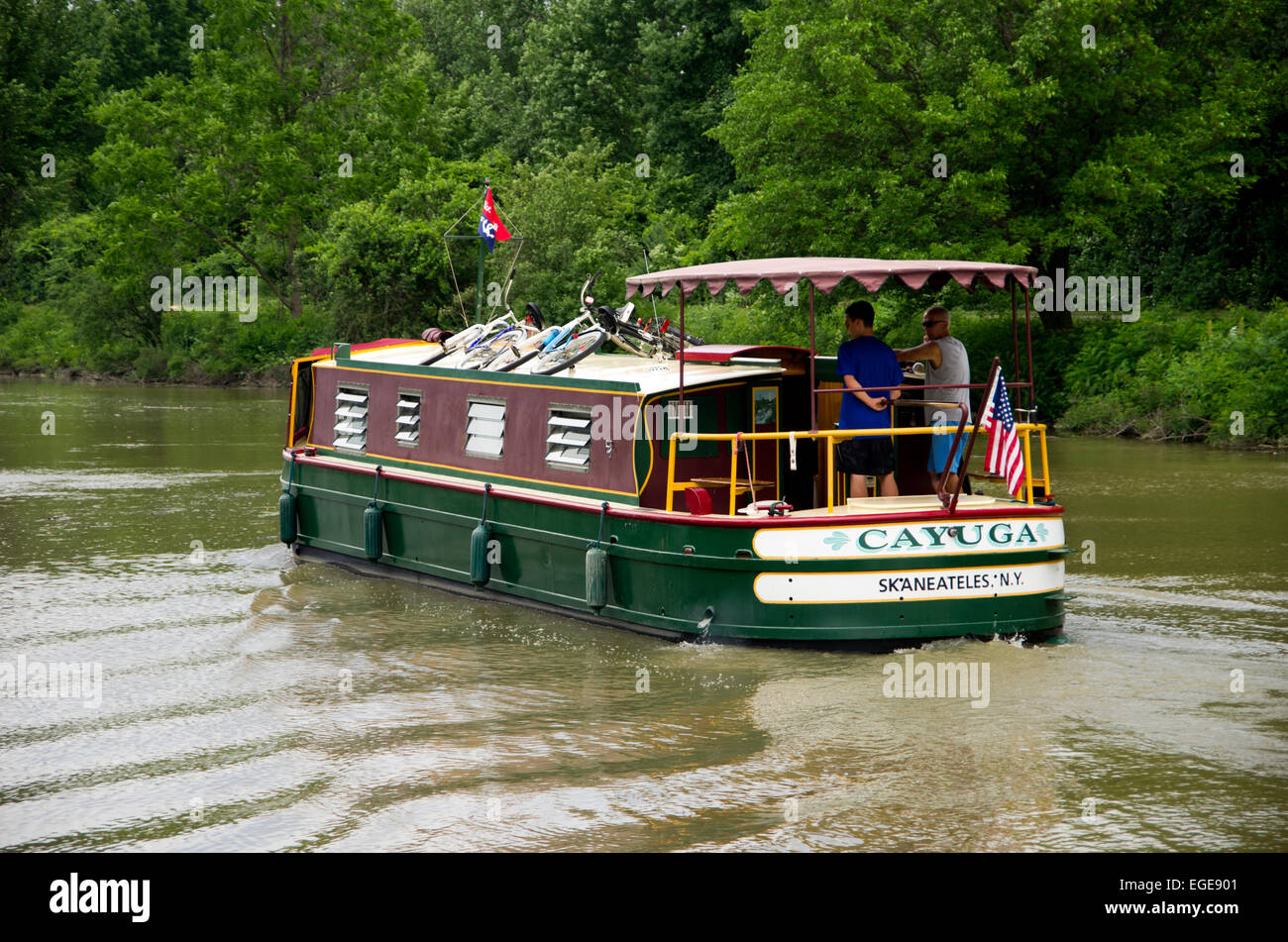 Charter cruises on Erie Canal. Two holiday makers drive from stern, back of the boat. Stock Photo