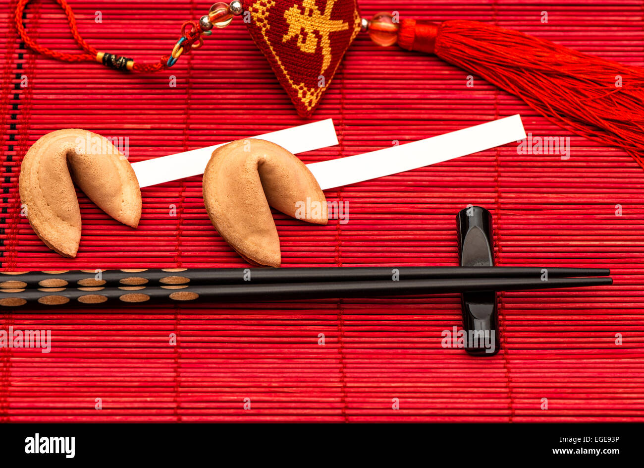 Chinese new years lucky charm, fortune cookies and black chopsticks on red bamboo mat Stock Photo