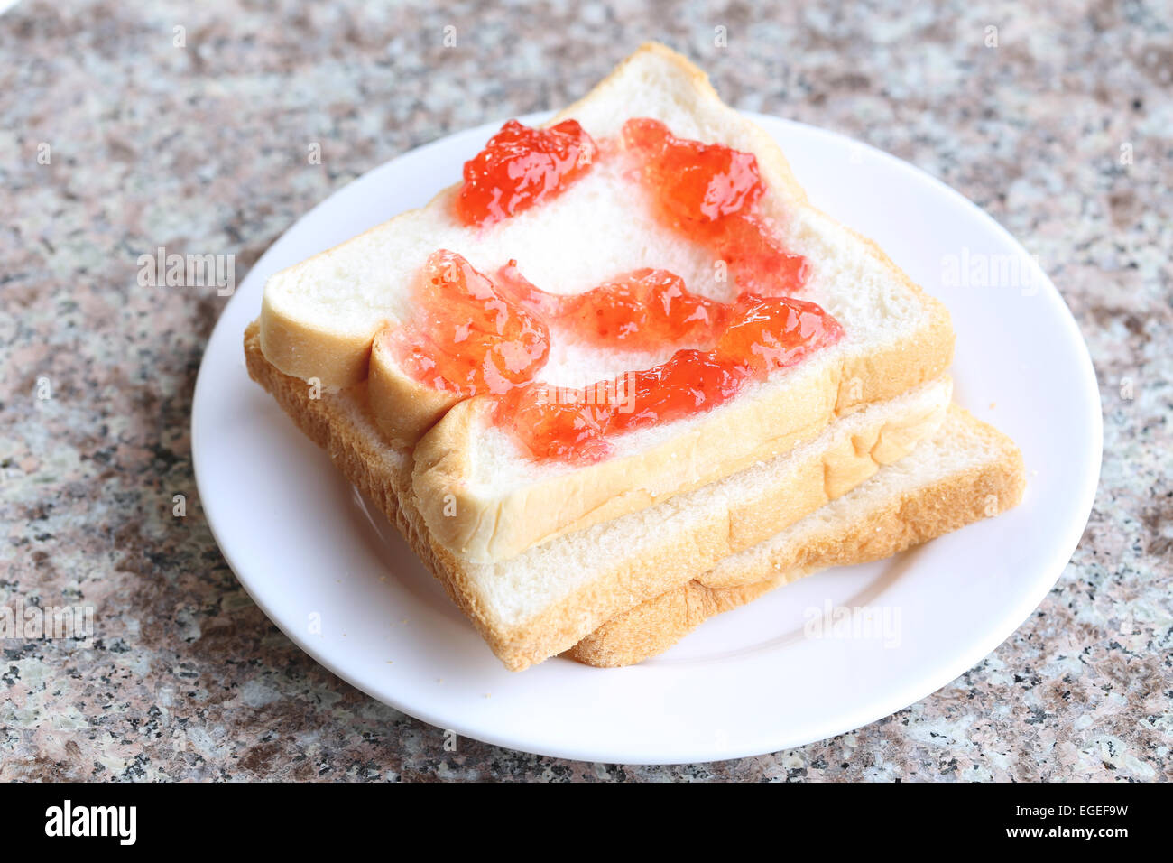 Bread with strawberry jam in white dish. Stock Photo