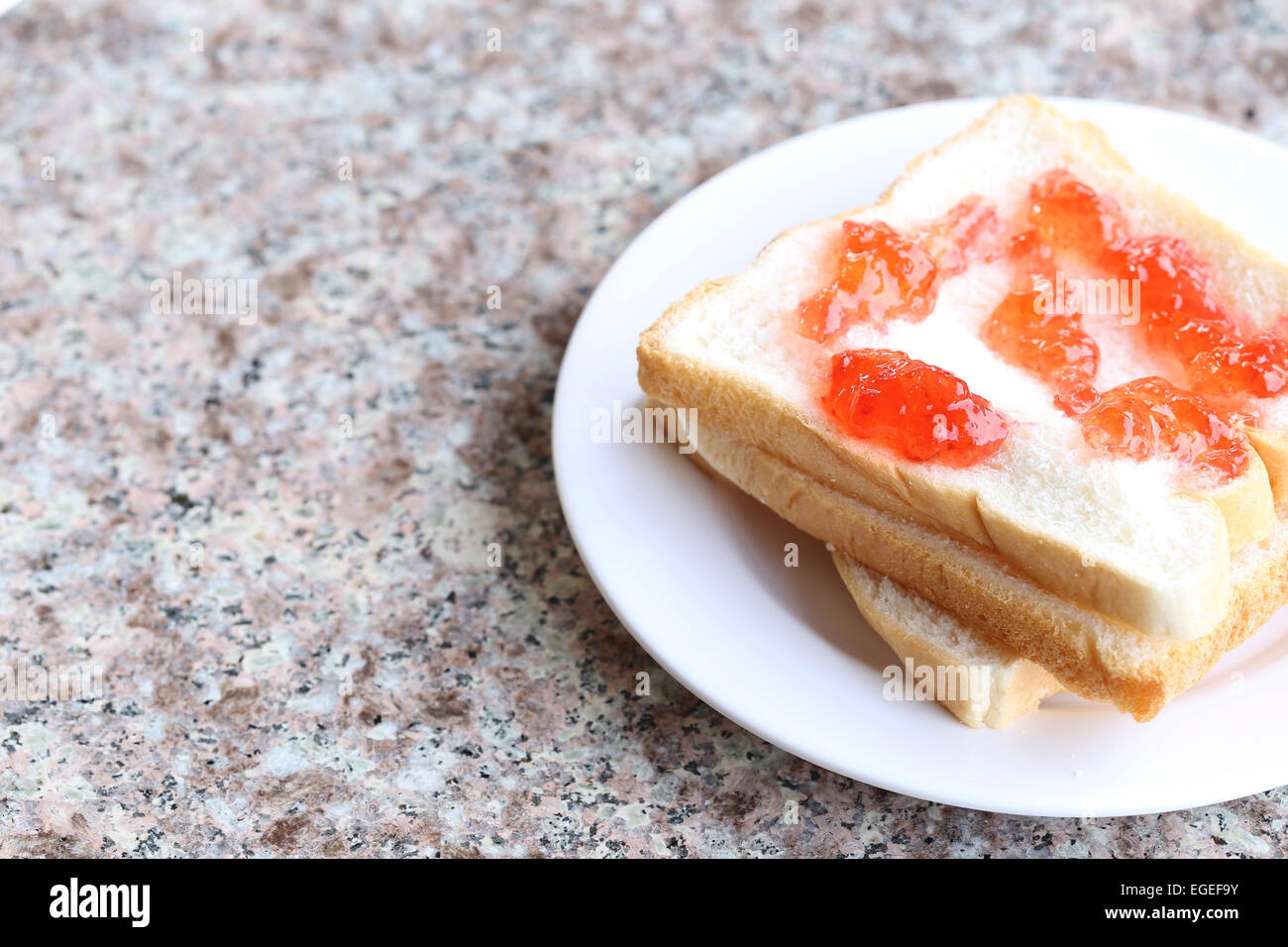 Bread with strawberry jam in white dish. Stock Photo