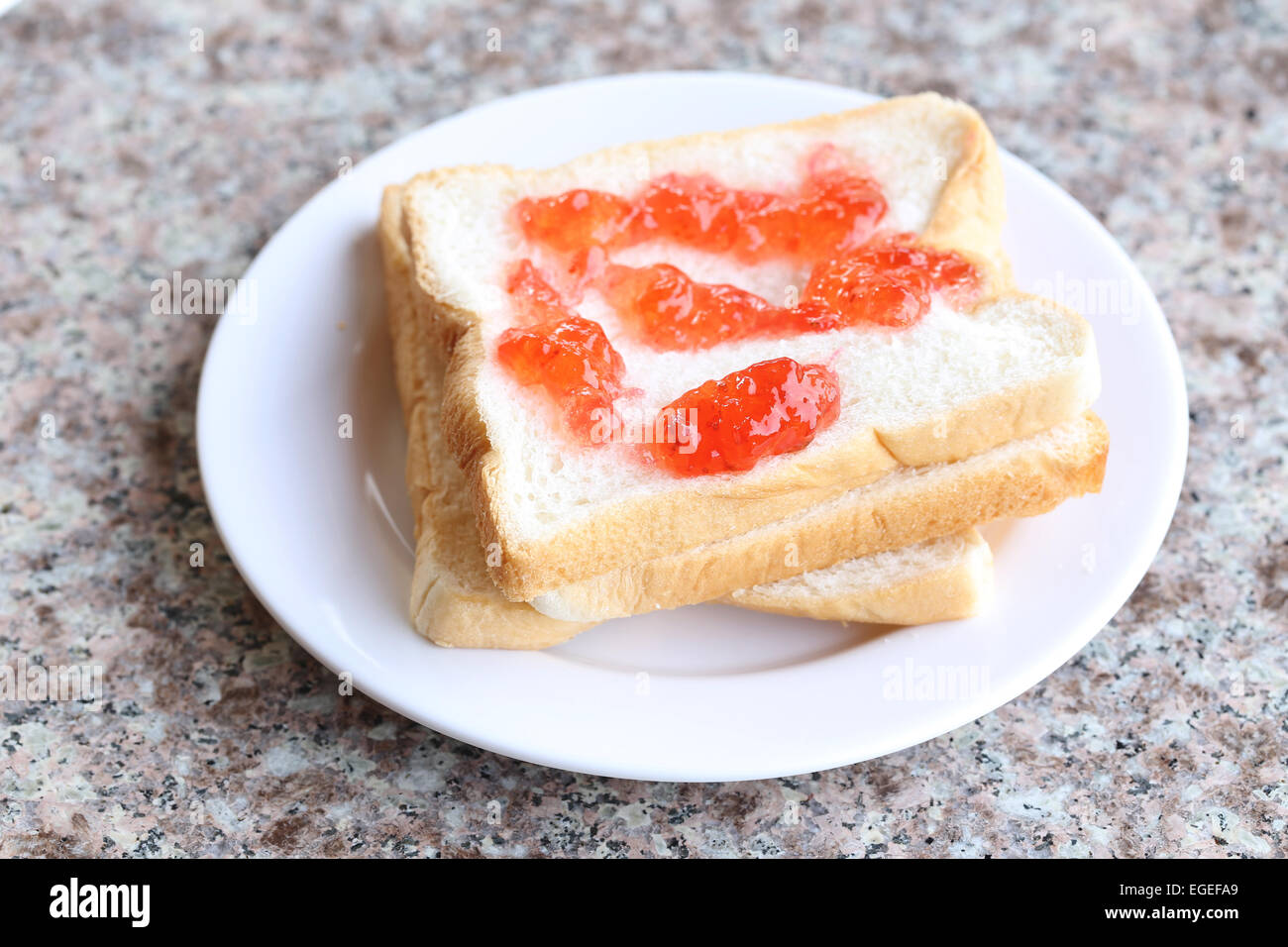 Bread with strawberry jam in white dish. Stock Photo