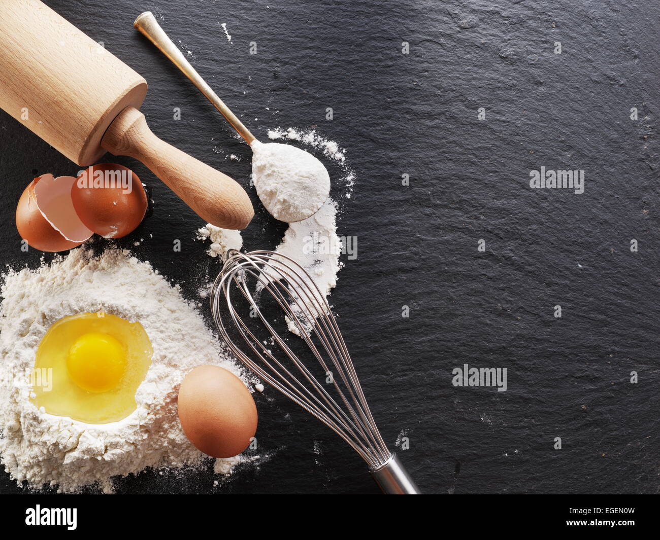 Dough preparation. Baking ingredients: egg and flour on black board. Stock Photo
