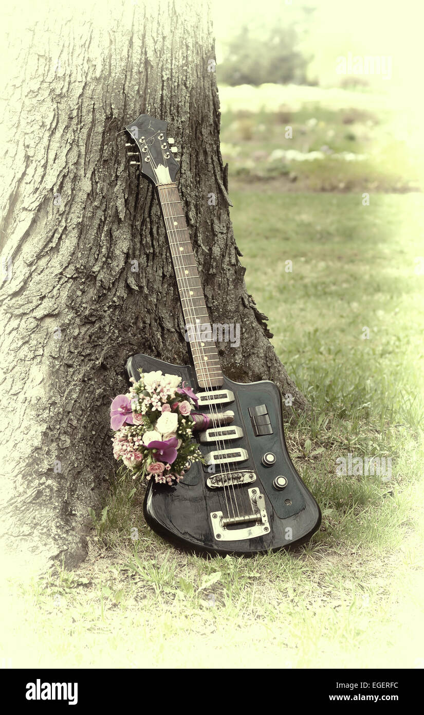Electric guitar with a bunch of flowers near a tree. Retro effect is added  Stock Photo - Alamy