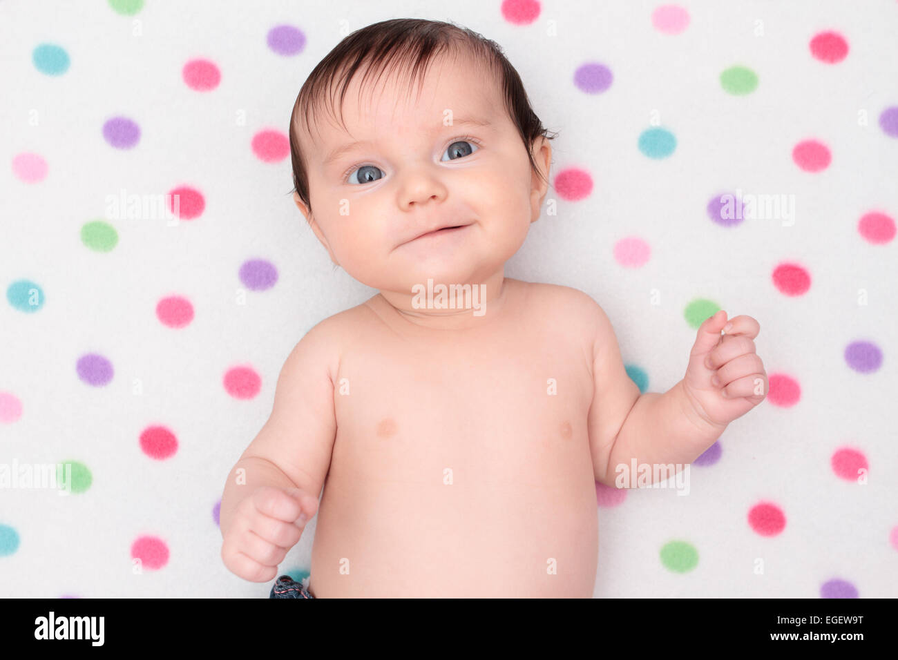 Little baby girl lying on blanket with colorful polka dots Stock Photo