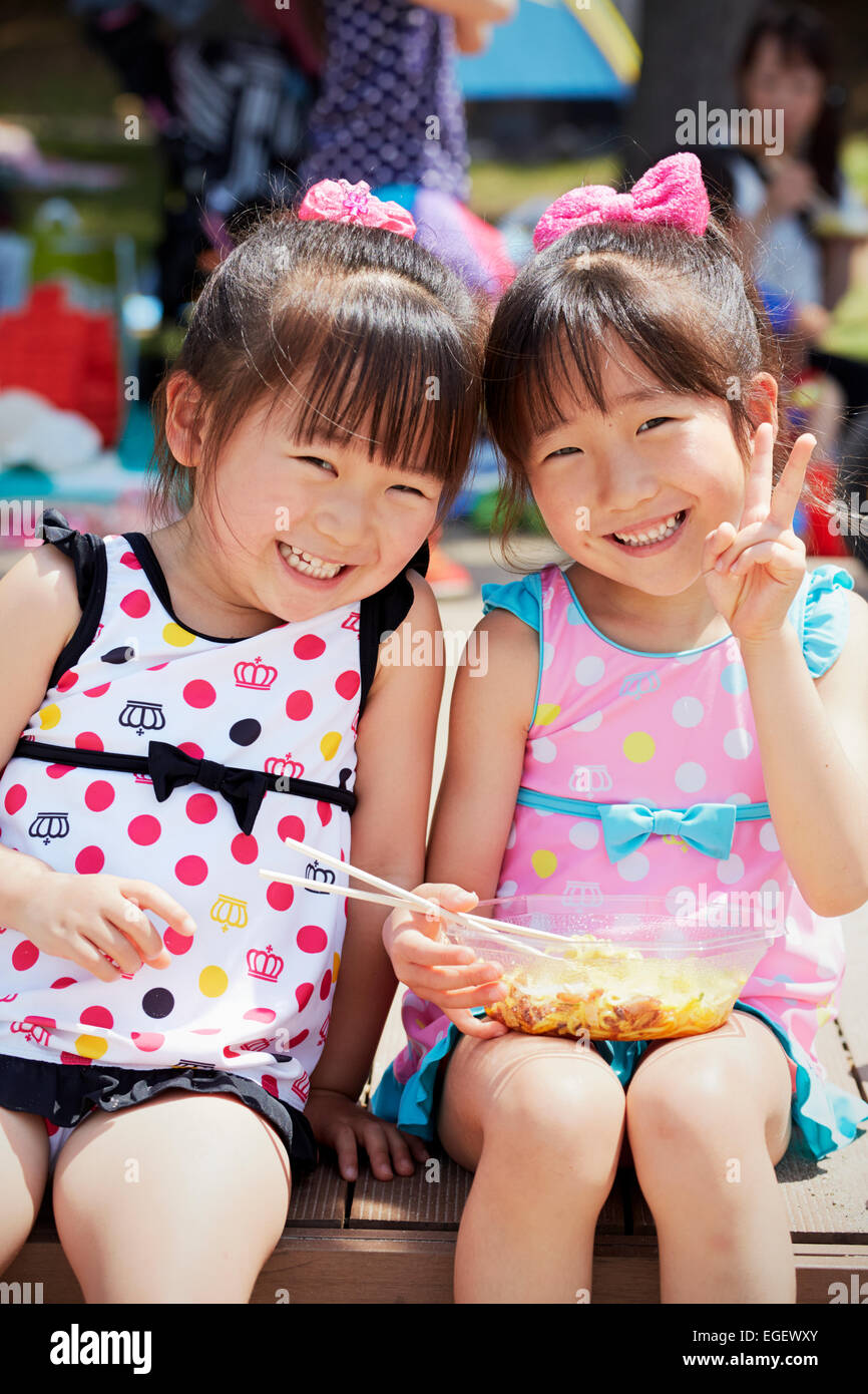 Two girls smiling and eating noodles, Odaiba, Tokyo, Japan Stock Photo