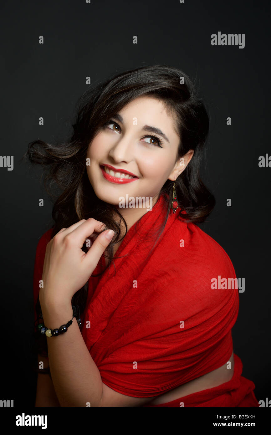 Beautiful smiling hispanic girl in red on black background Stock Photo