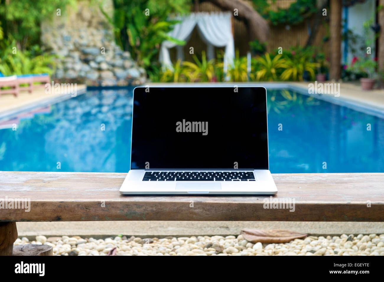 Laptop on a bench by the pool, working on vacation with mobility concept Stock Photo