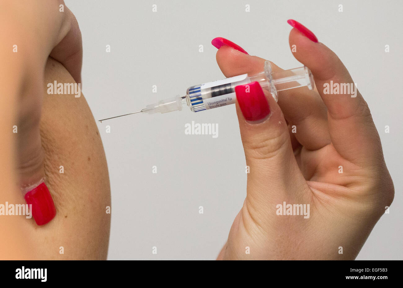 Berlin, Germany. 24th Feb, 2015. A man is vaccinated with a measles shot by a doctor's assistant wearing red nail polish in Berlin, Germany, 24 February 2015. PHOTO: LUKAS SCHULZE/dpa/Alamy Live News Stock Photo