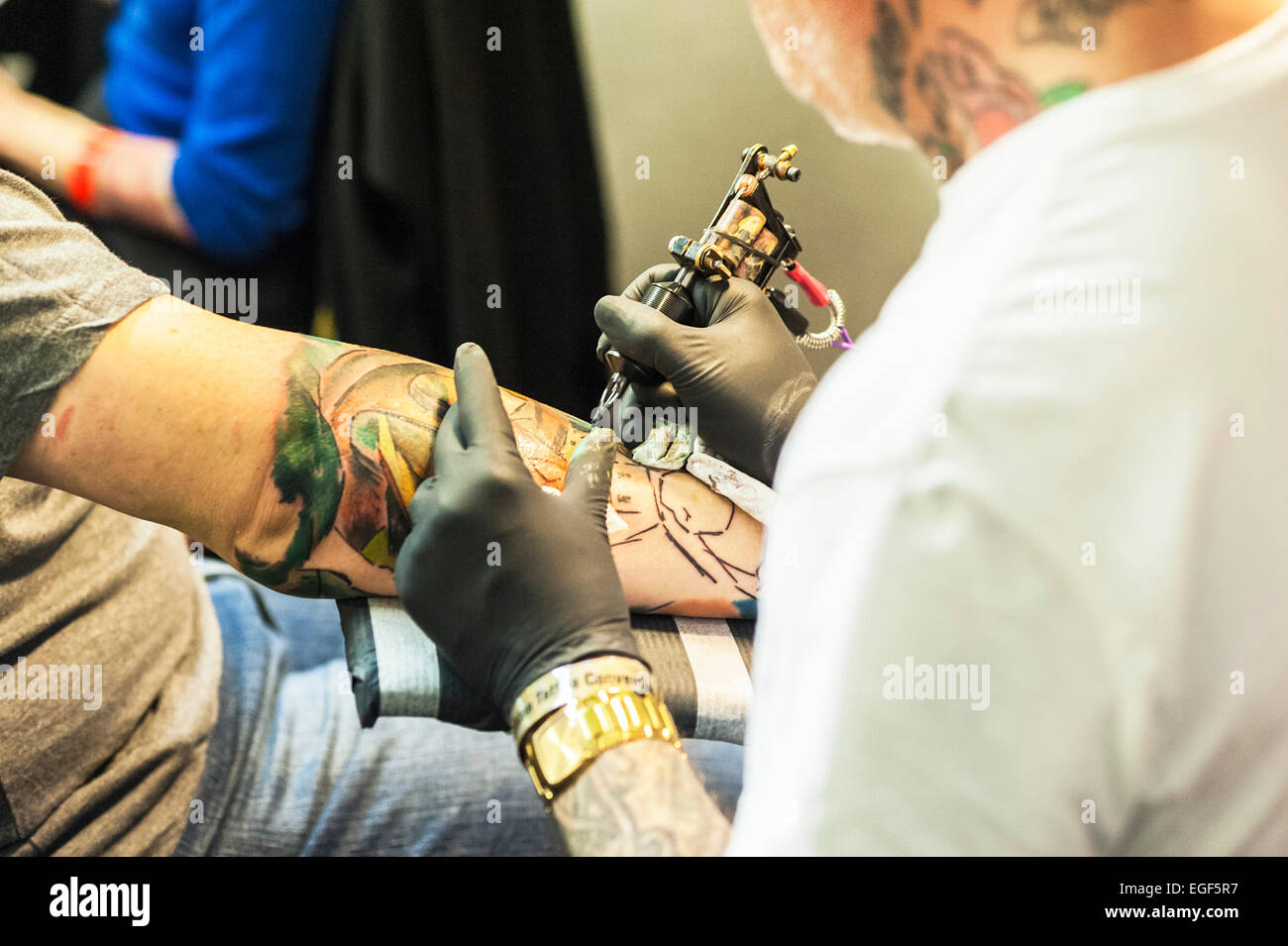 A man being tattooed on his arm at the Brighton Tattoo Convention. Stock Photo