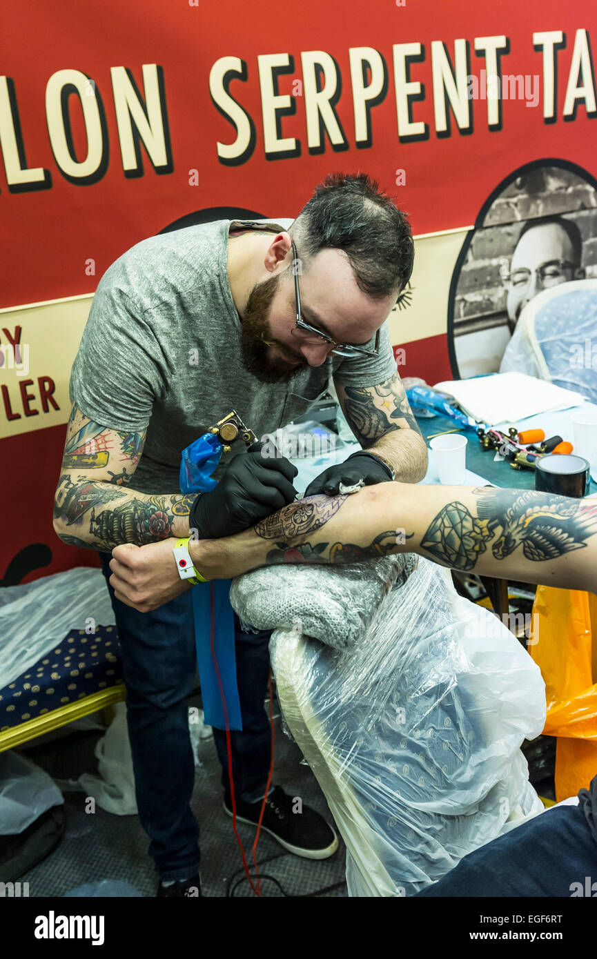A man being tattooed on his arm at the Brighton Tattoo Convention Stock
