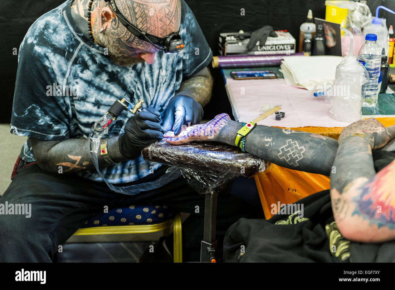 A man being tattooed on the palm of his hand at the Brighton Tattoo Convention. Stock Photo