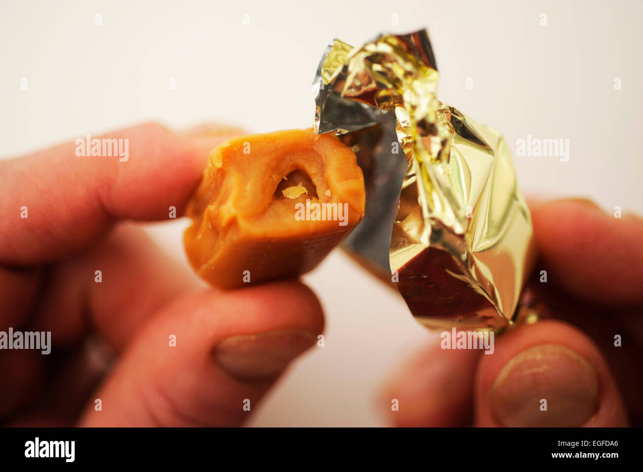 Male Unwrapping a Toffee Sweet Stock Photo