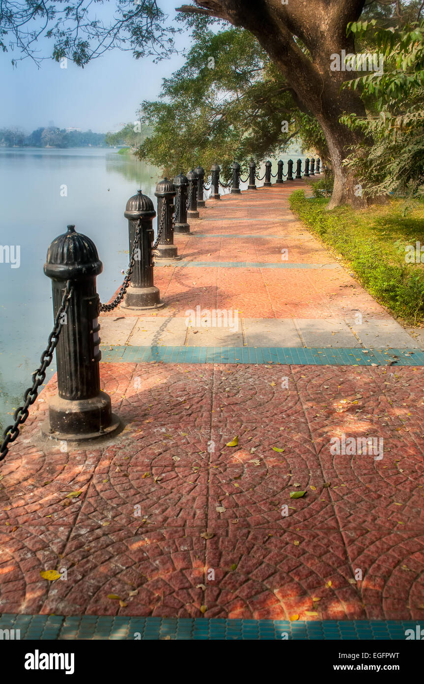 Garden paved path with iron chain and railings by lake with copy space Stock Photo