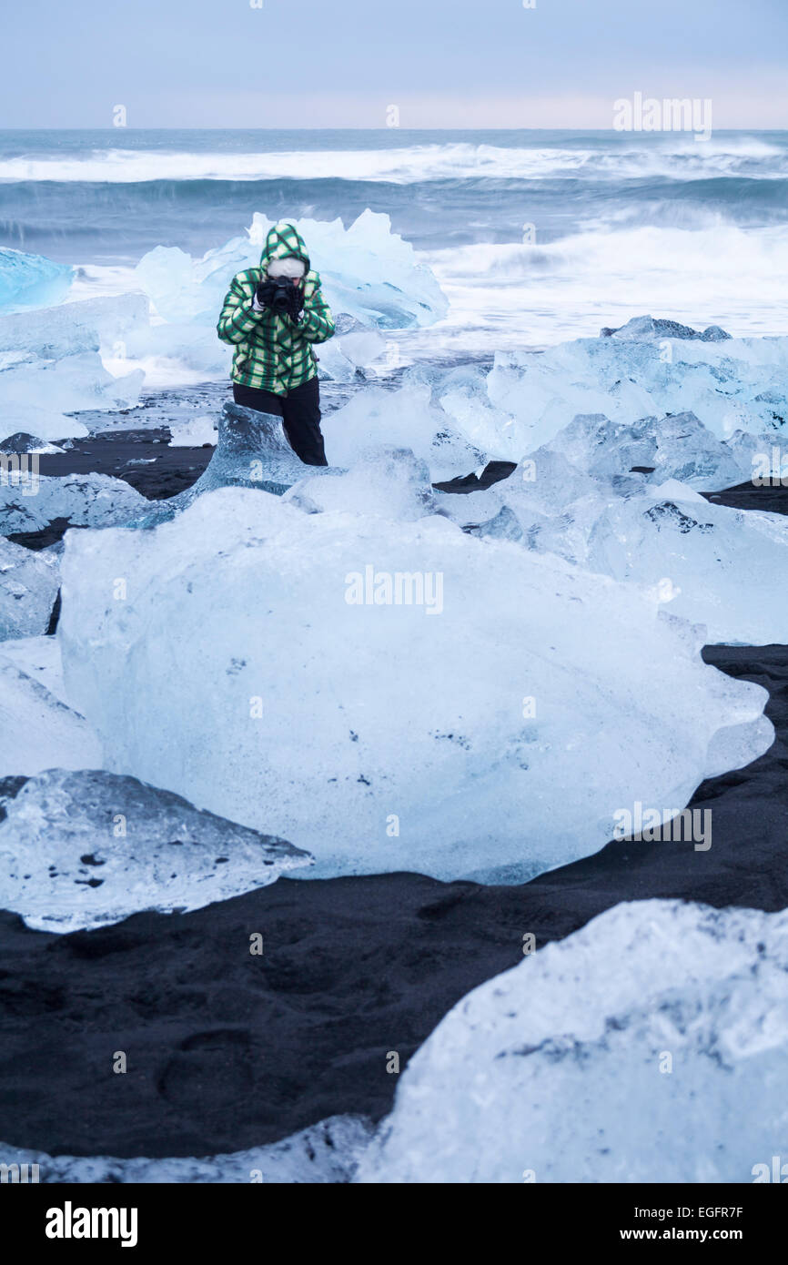 Person photographer taking photos of ice at Jokulsarlon Glacial beach, Diamond beach, Iceland in February Stock Photo