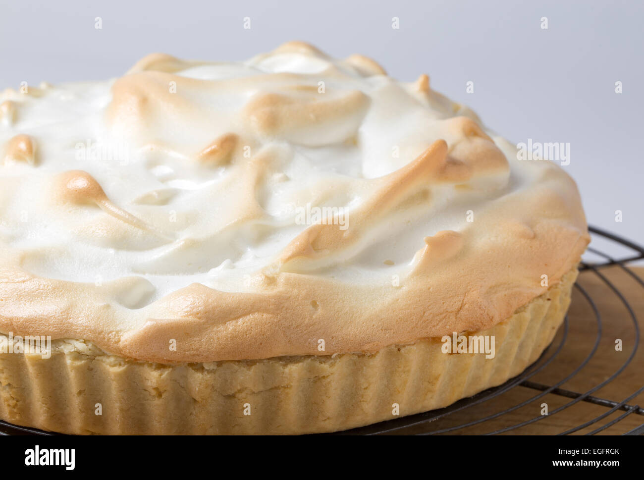 Homemade lemon meringue pie, a classic of European dessert cuisine, on a cooling rack fresh from the oven Stock Photo
