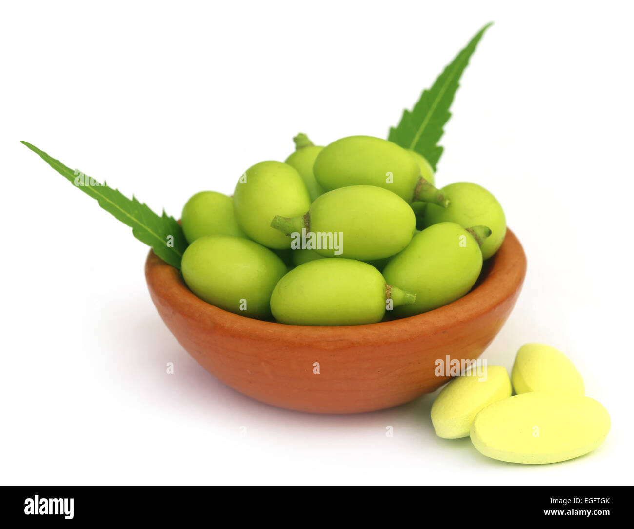 Medicinal neem fruits with tablets over white background Stock Photo