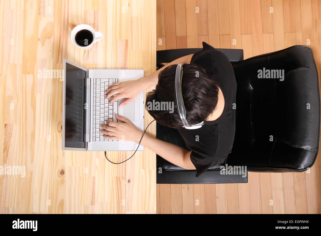 A young hispanic man working on a laptop computer while listening to ...