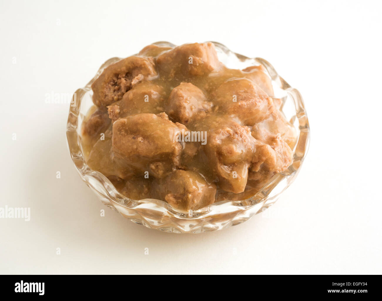 Chicken dog food in a small decorative bowl atop a white floor with natural light. Stock Photo