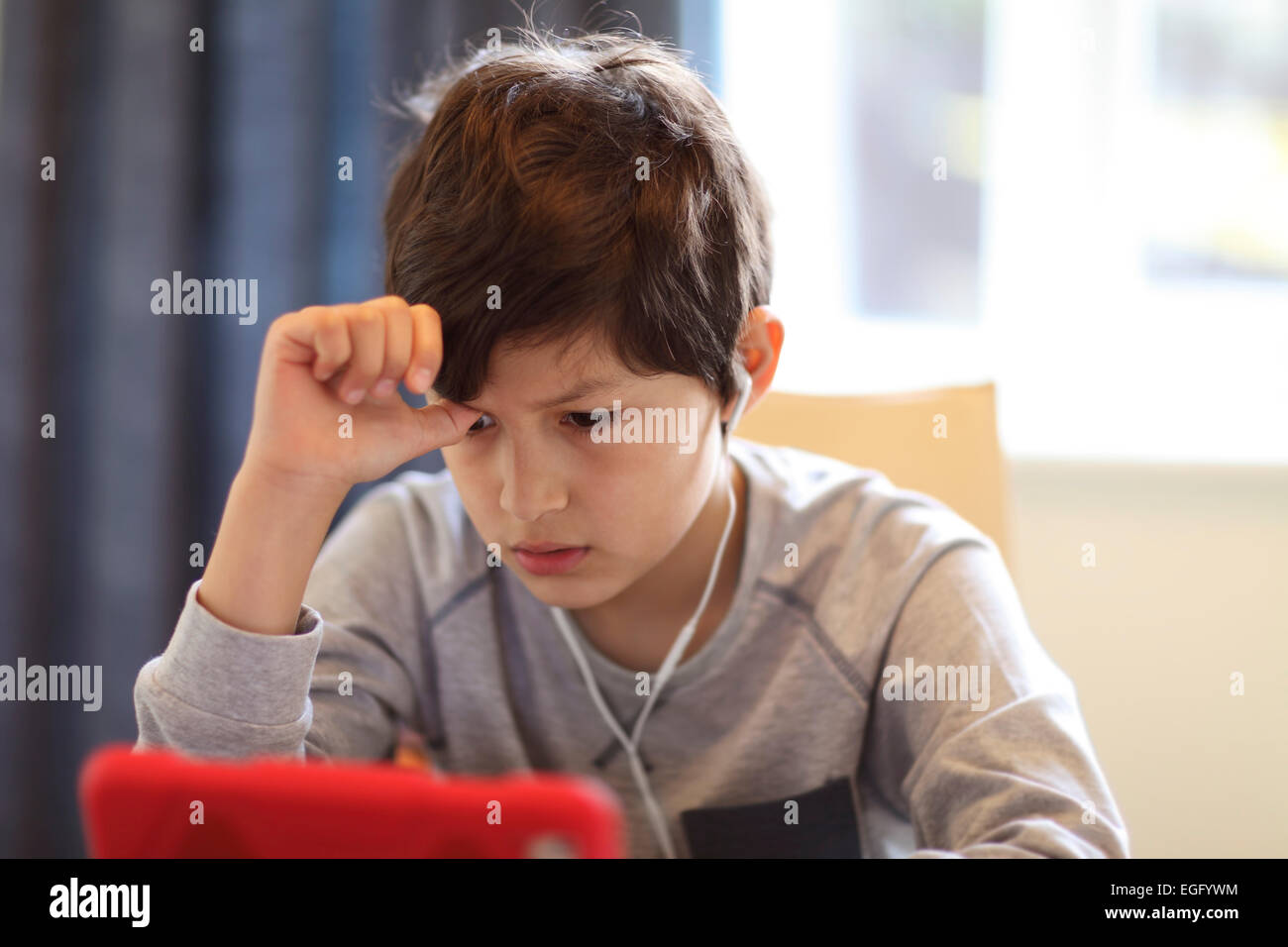 Serious young boy playing with tablet computer Stock Photo
