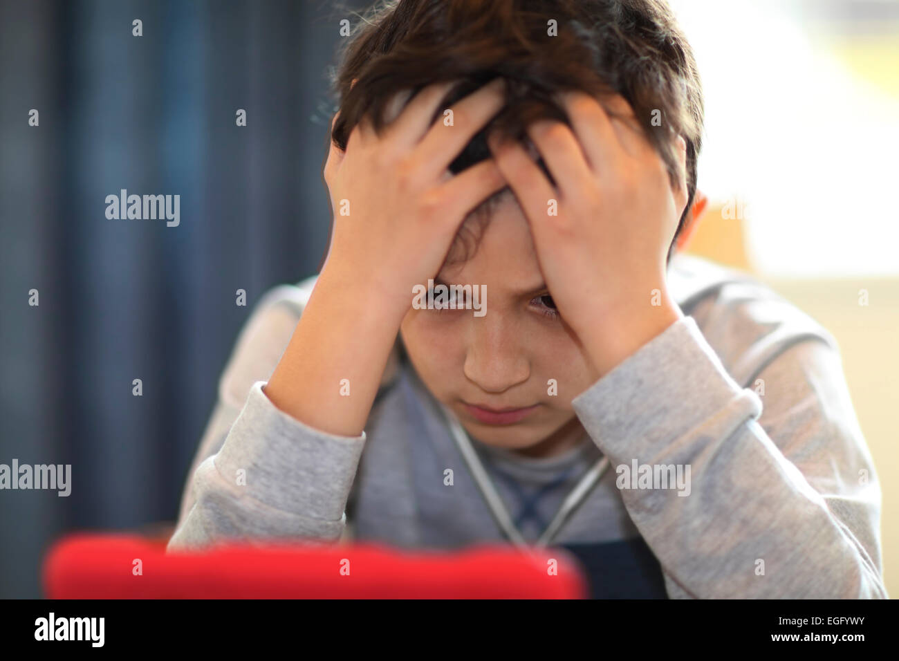 Confused or tired young boy playing with tablet computer Stock Photo