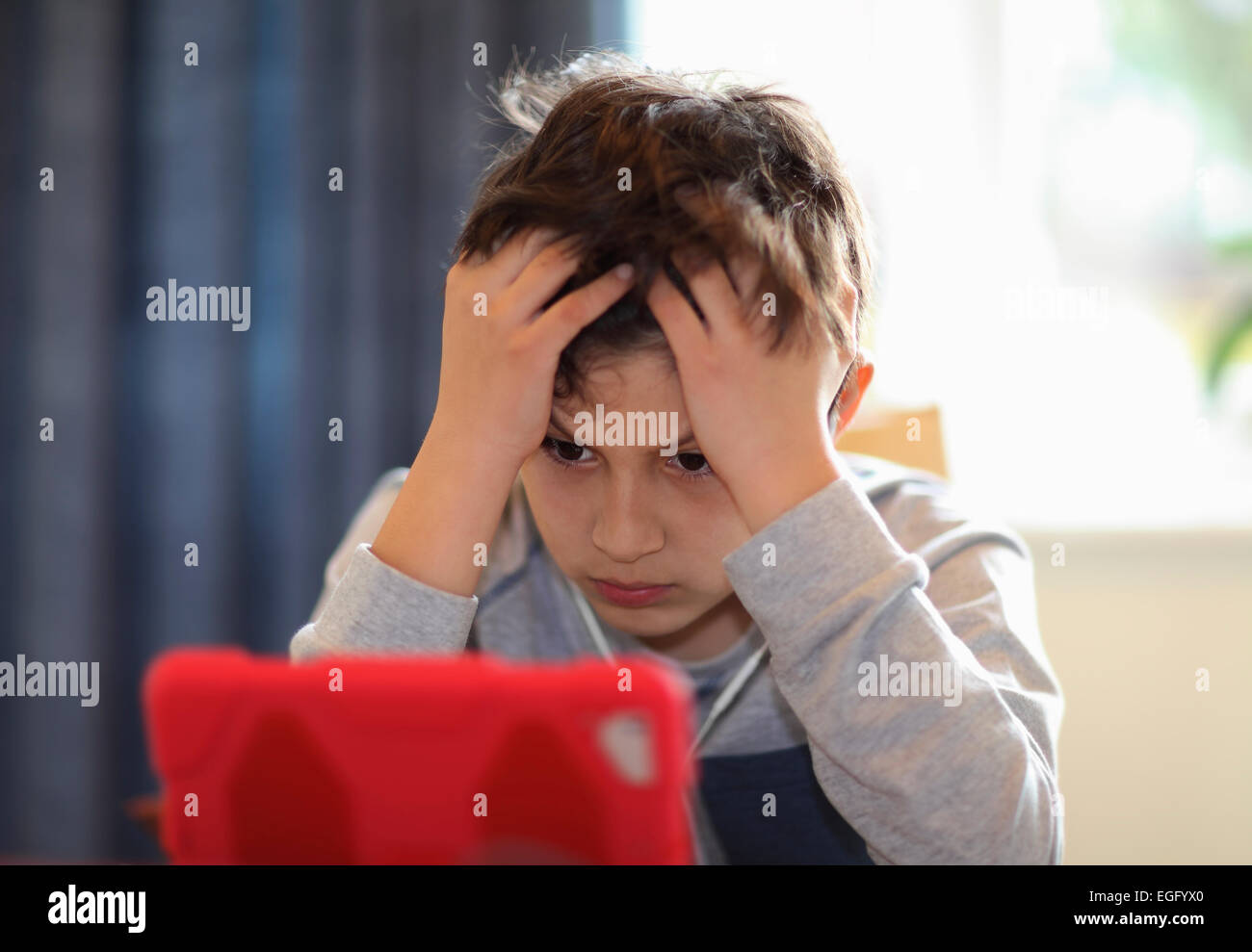 Concentrating young boy playing with tablet computer Stock Photo