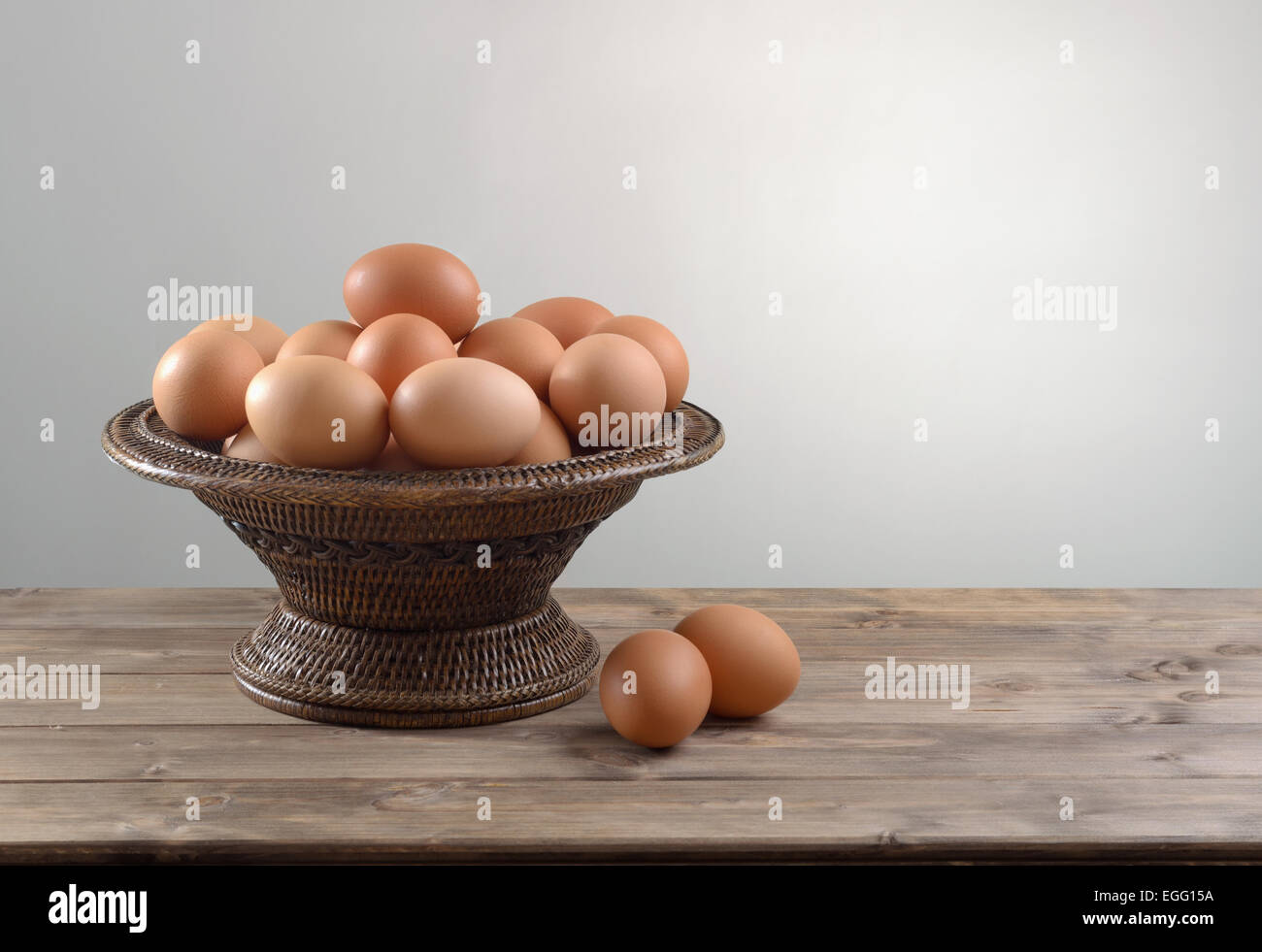 pile of chicken eggs in a wicker bowl on wooden table Stock Photo