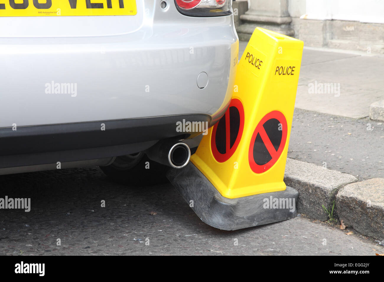 Car badly parked against a Police No Parking cone Stock Photo