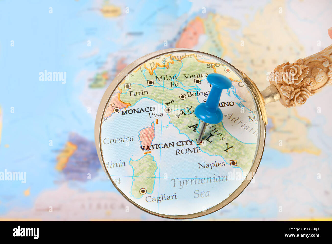 Blue tack on map of Europe with magnifying glass looking in on Rome, and Vatican City, Italy Stock Photo