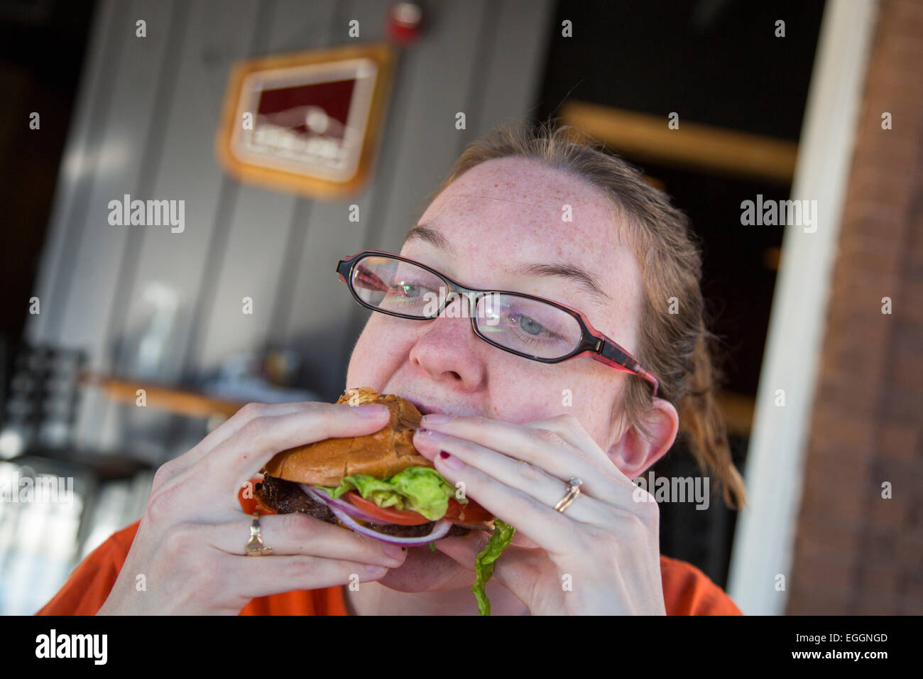 Wheat Ridge, Colorado - A young woman tries to get her mouth around a cheeseburger at the Colorado Plus Brew Pub. Stock Photo