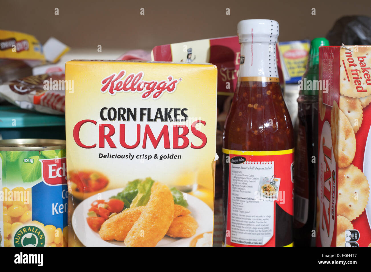 A box of Kellogs Corn Flakes Crumbs in the pantry with other groceries and food stuffs. Stock Photo