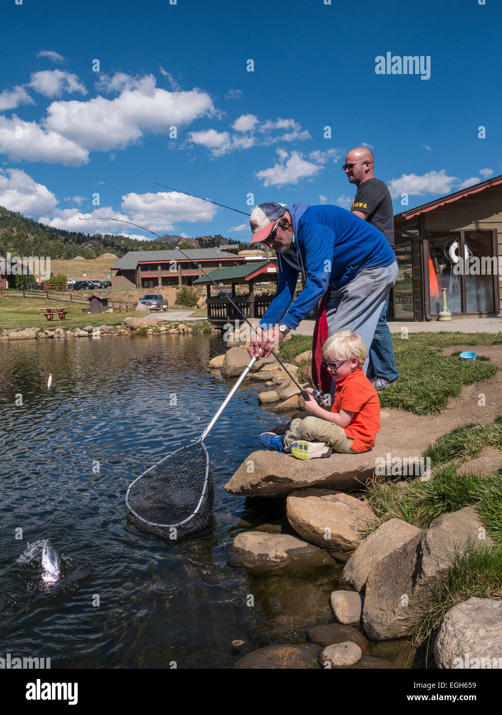 Employee helps young boy land his catch from the pond at Trout Haven