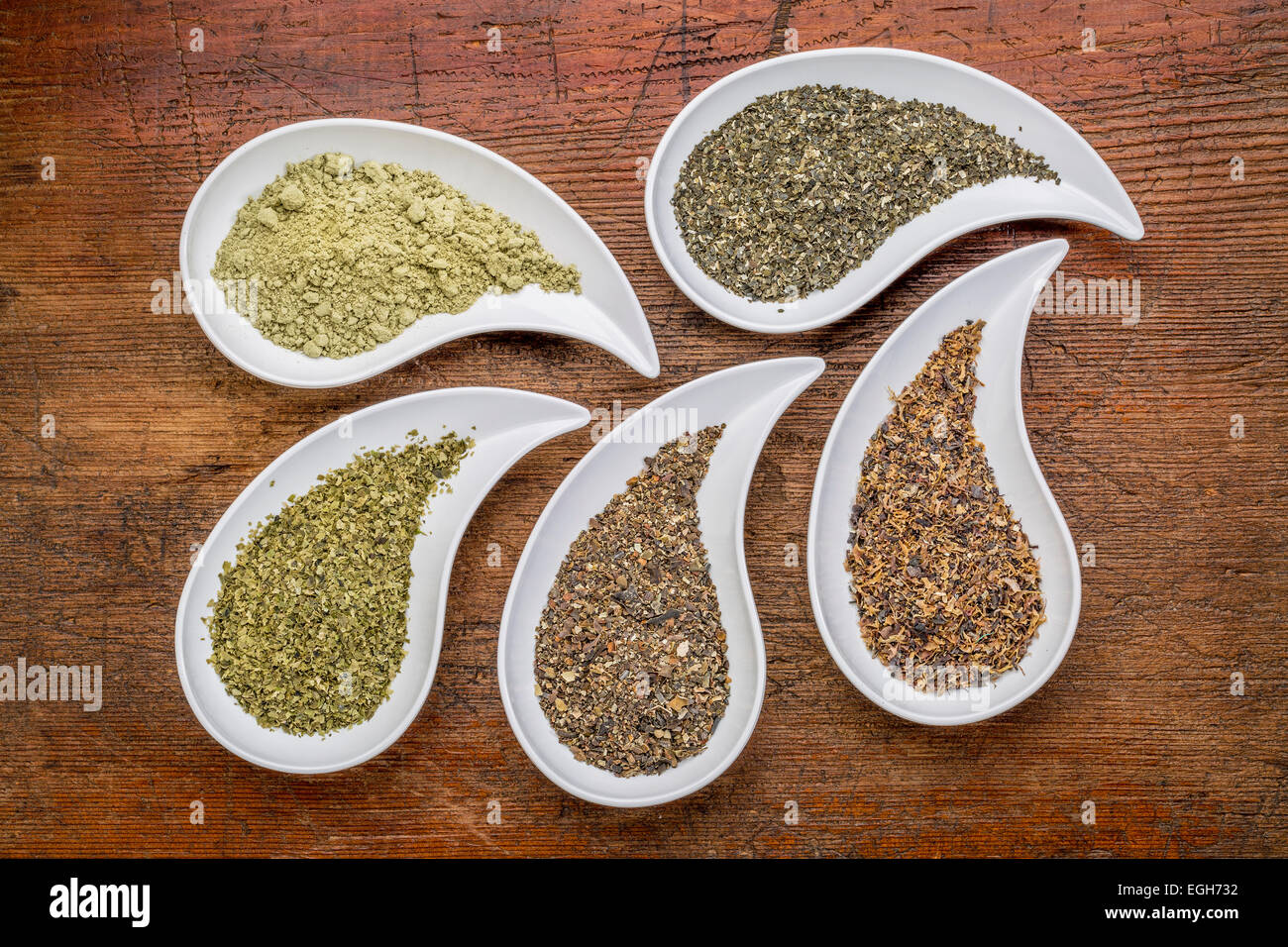 teardrop shaped bowls of seaweed diet supplements (bladderwrack, sea lettuce, kelp, wakame and Irish moss) on a grunge wood Stock Photo