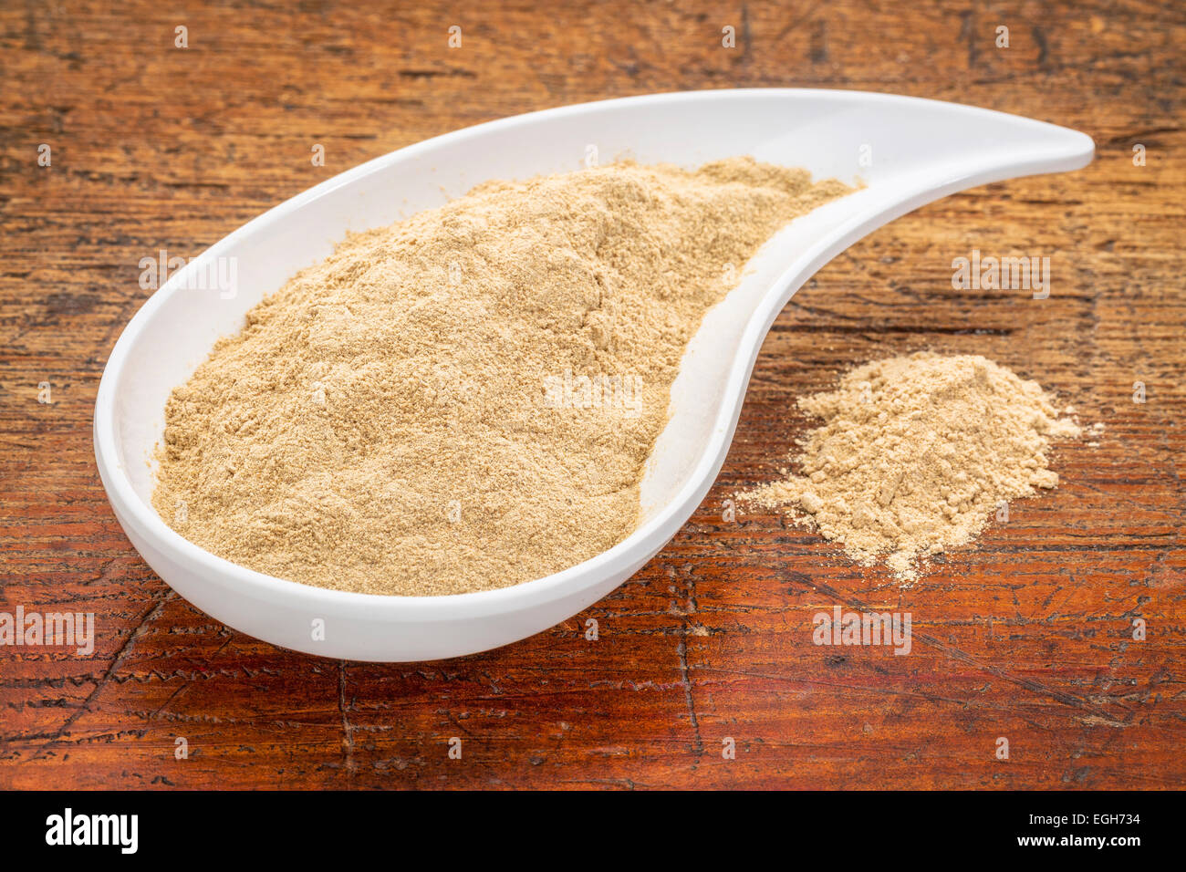 maca root powder in a teardrop shaped bowl against grunge wood Stock Photo