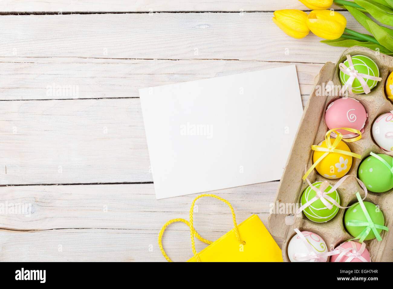 Easter background with colorful eggs, yellow tulips and greeting card ...