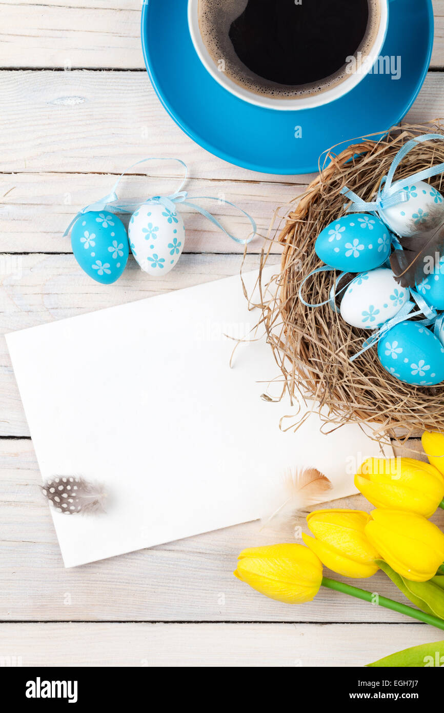 Easter background with blue and white eggs in nest, yellow tulips and ...