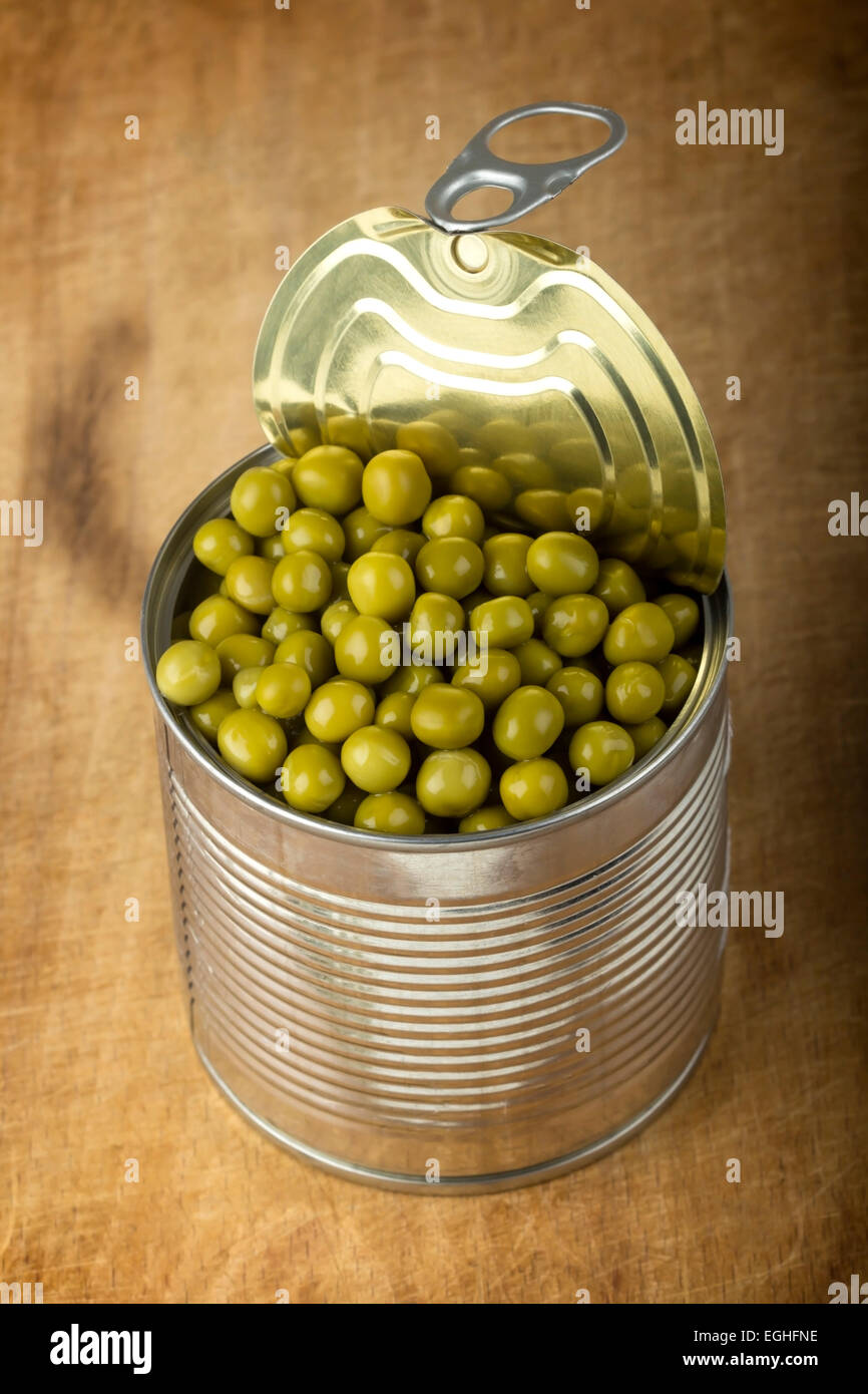 Opened tin with green peas over wood background Stock Photo
