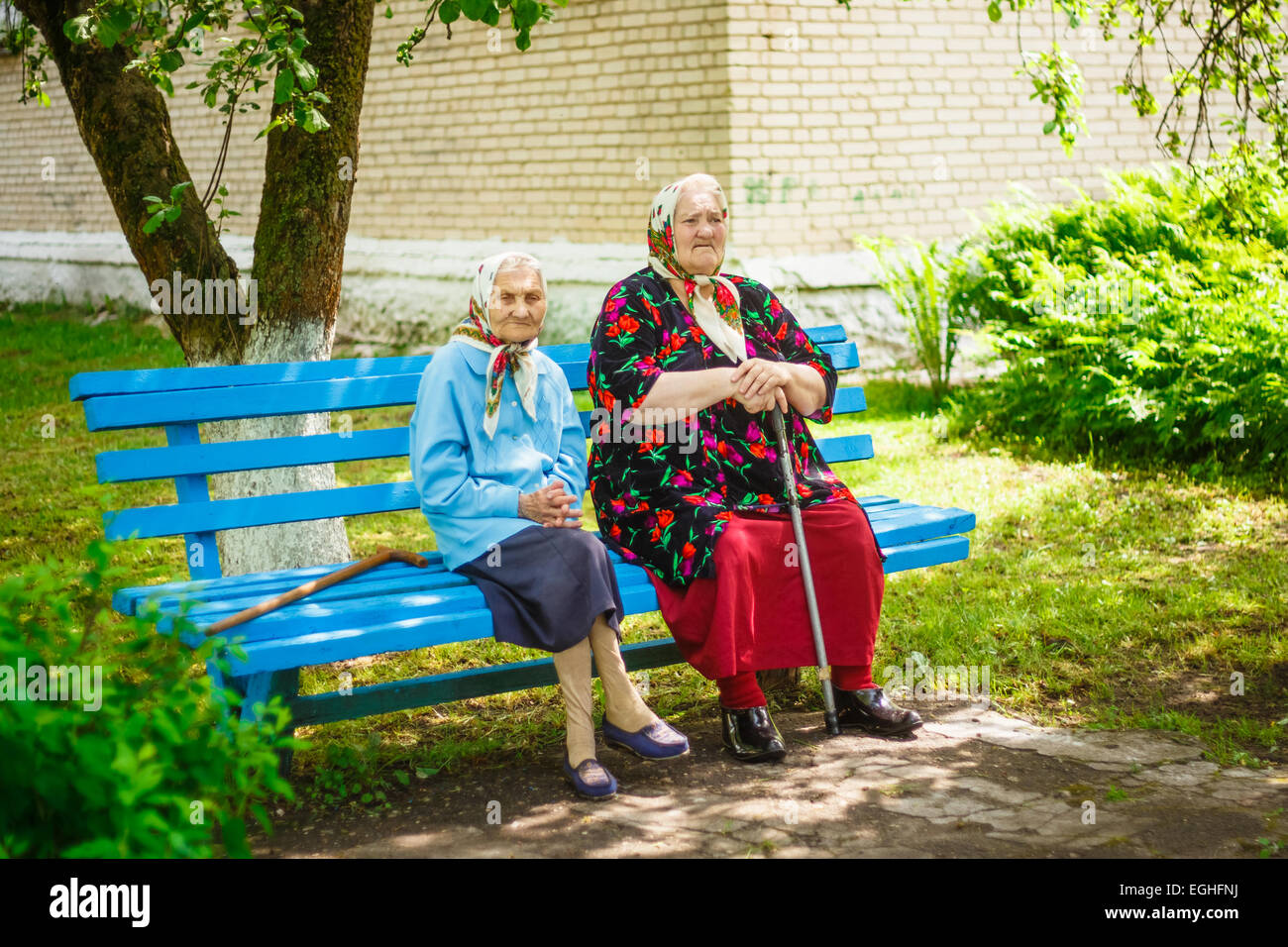 Two elderly women of the Belarusian village sits on wooden bench ...