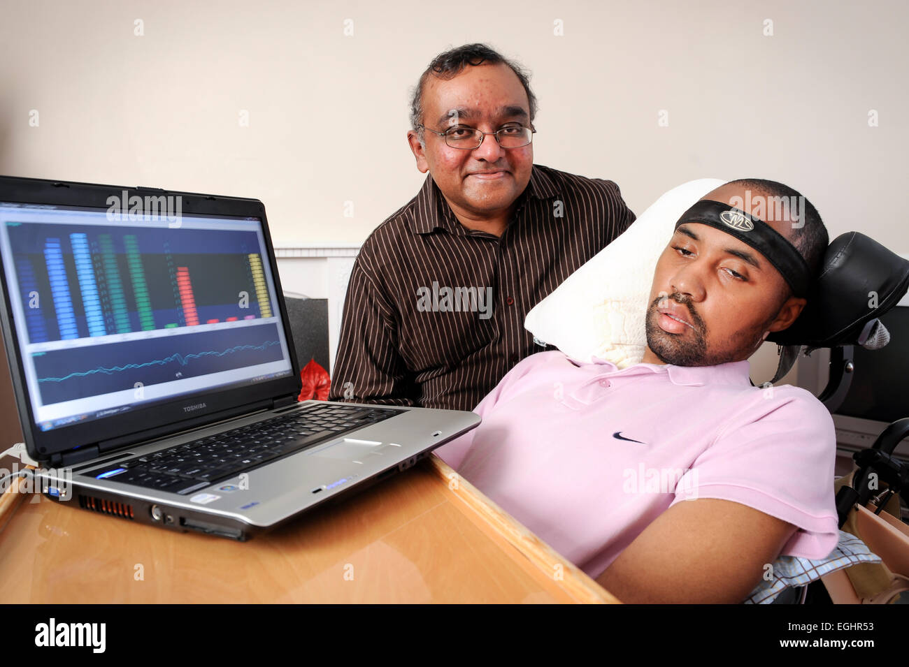 Richard Gregory has Locked-in Syndrome is pictured with Dr Gnanayathum, who's developed a device which interprets the brainwaves Stock Photo