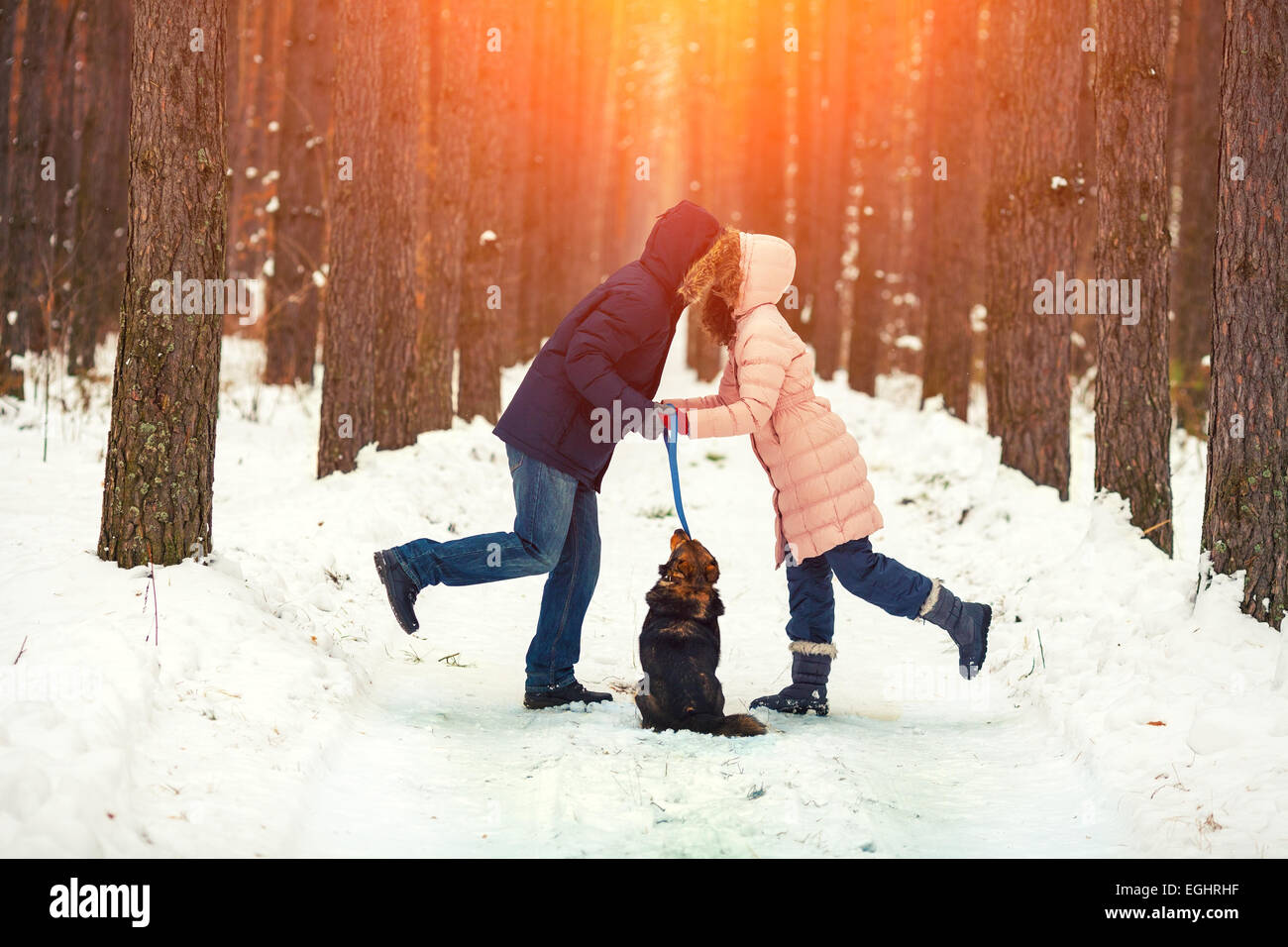 Young couple in love with dog walking in the snowy forest and kissing ...