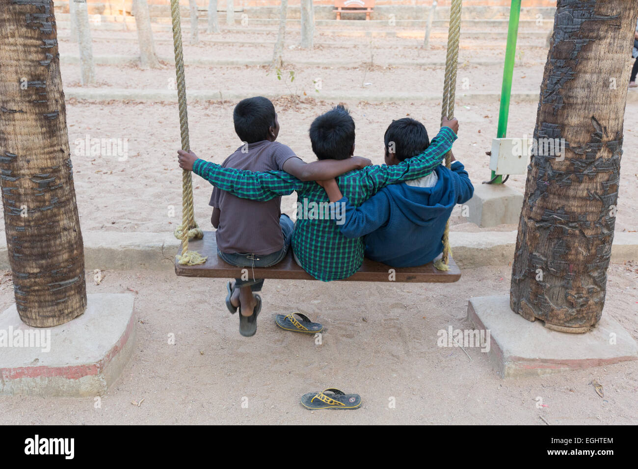Three Indian Boys on a wooden rope swing at Shilparamam, a popular
