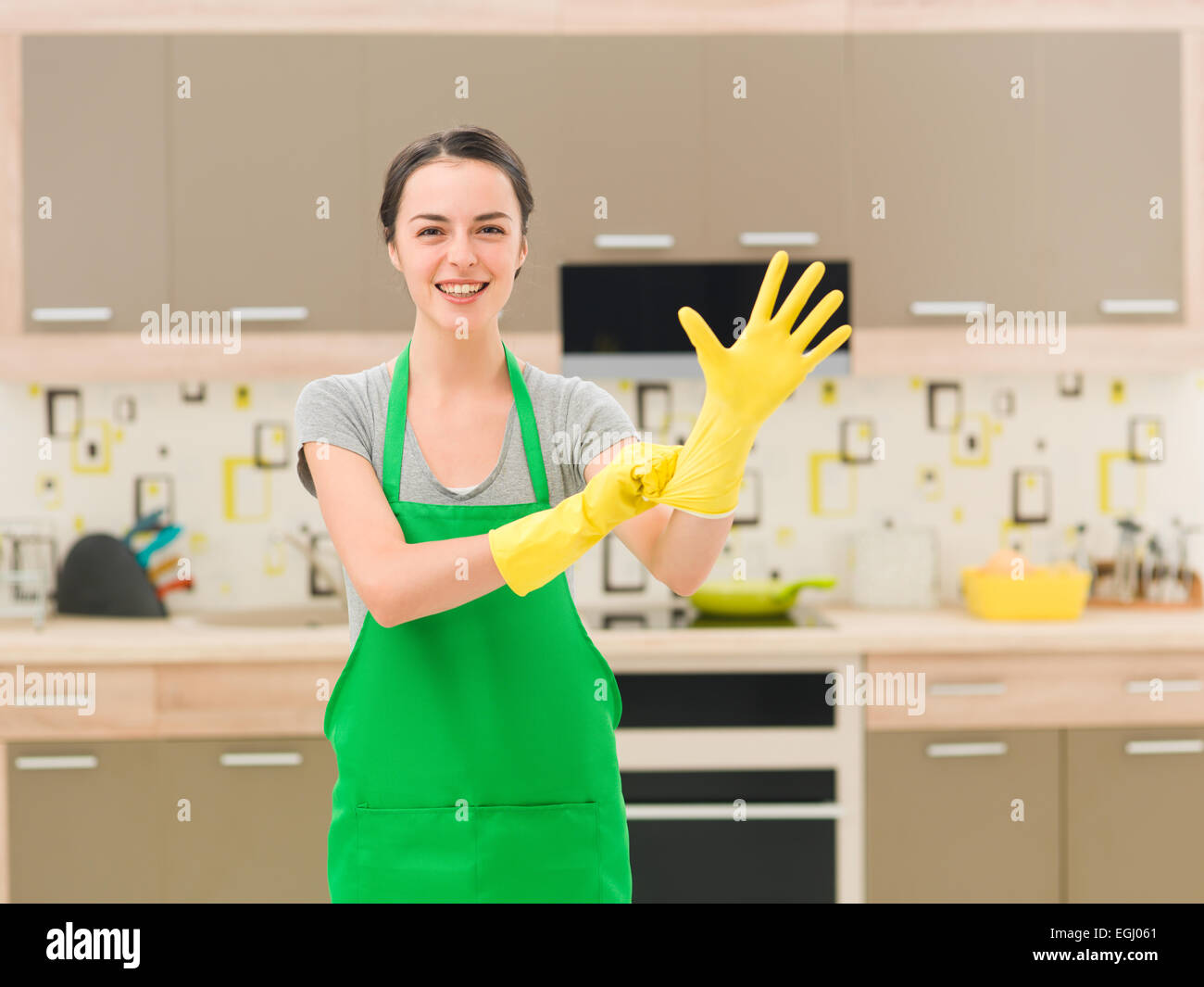 young happy woman putting rubber gloves and getting ready for cleaning Stock Photo